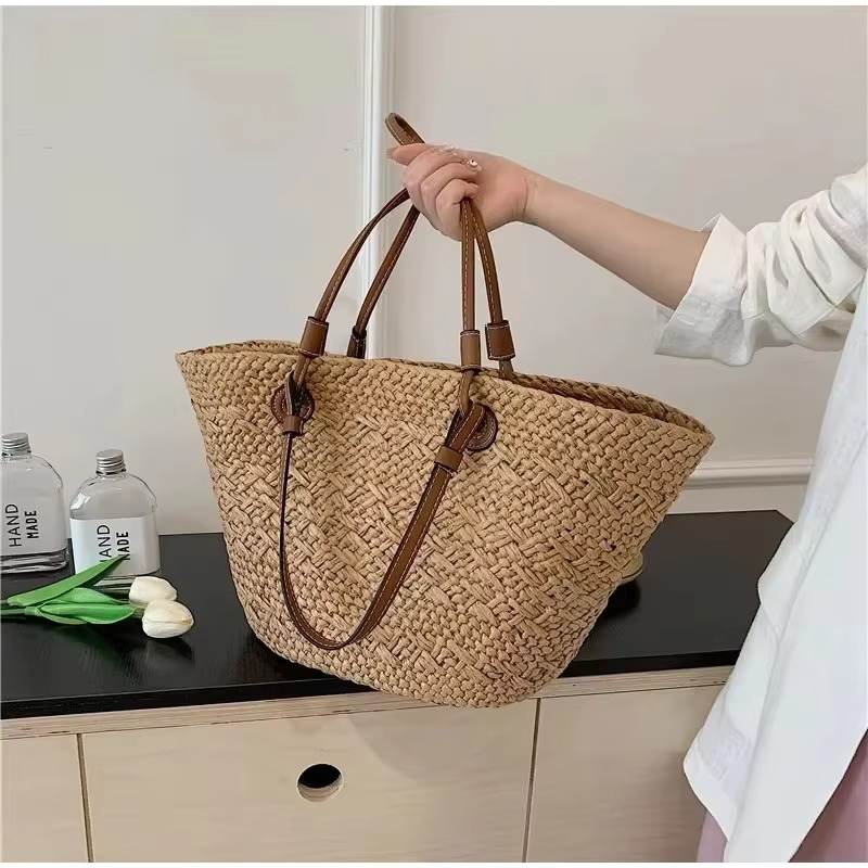 Sac en paille style français grande capacité Manon avec anses en cuir marron tenu par une main
