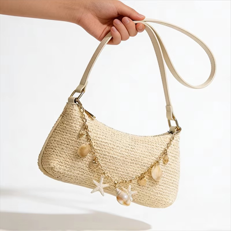 Sac en paille baguette beige avec bandoulière fine et chaînette décorée de breloques coquillages