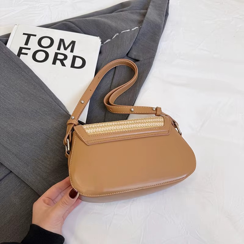 Sac en paille bandoulière avec rabat arrondi et bordure cuir camel modèle Océalie posé sur un tissu gris et blanc