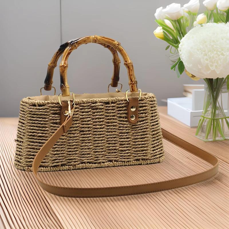 Sac en paille cabas avec poignée en bambou et bandoulière en cuir posé sur une table en bois clair