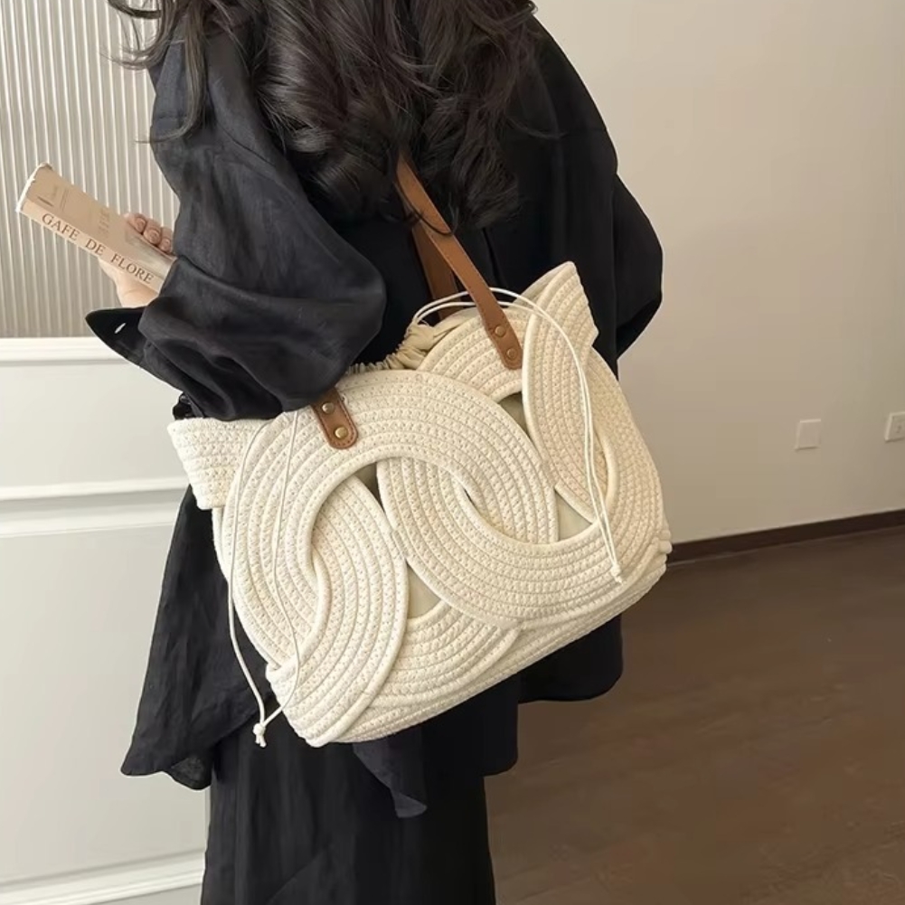 Sac en paille crochet beige avec motif feuilles tressées et anses en cuir marron porté par une femme
