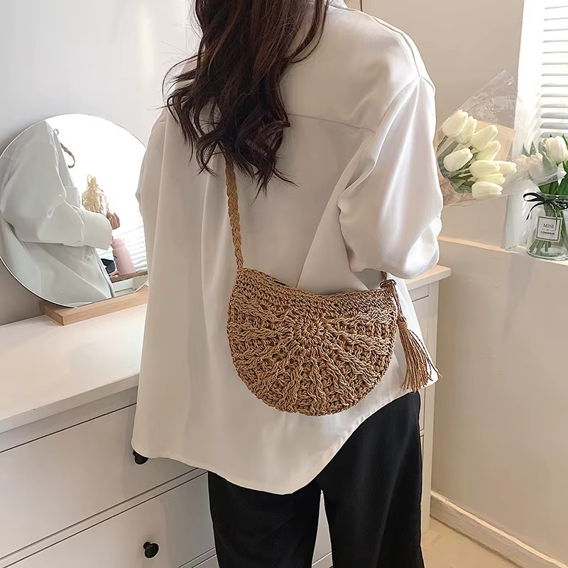 Sac en paille demi-cercle avec pompon et bandoulière porté sur l'épaule, modèle Amandine