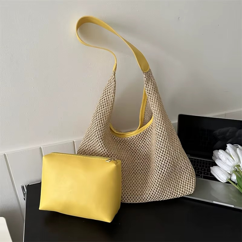 Sac en paille de plage tissée avec sangle fine jaune et pochette jaune posés sur une table