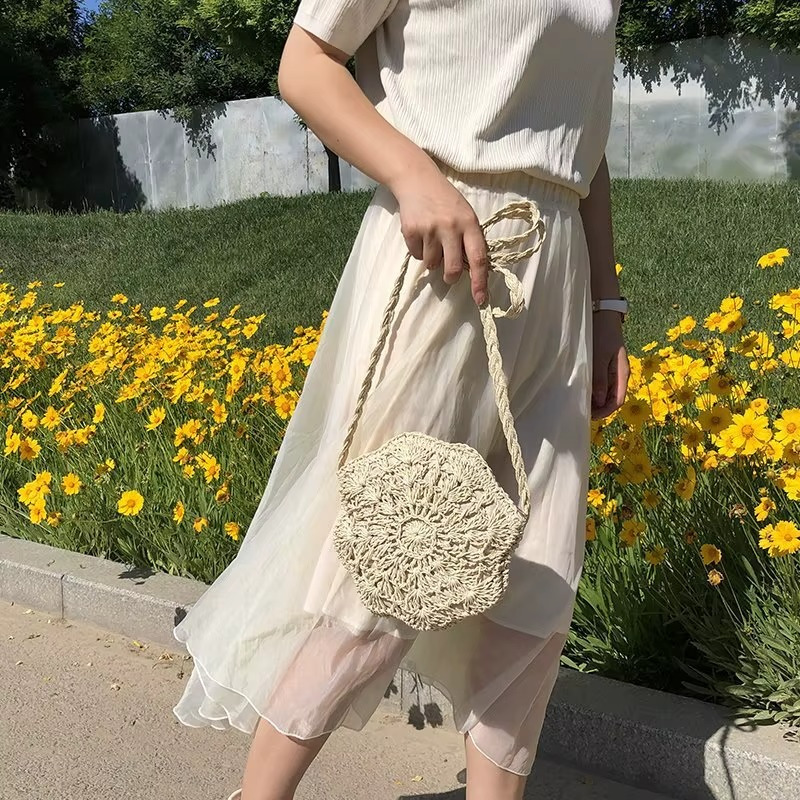 Sac en paille rond crochet dentelle plat couleur naturelle modèle Marguerite porté à la main avec bandoulière tressée