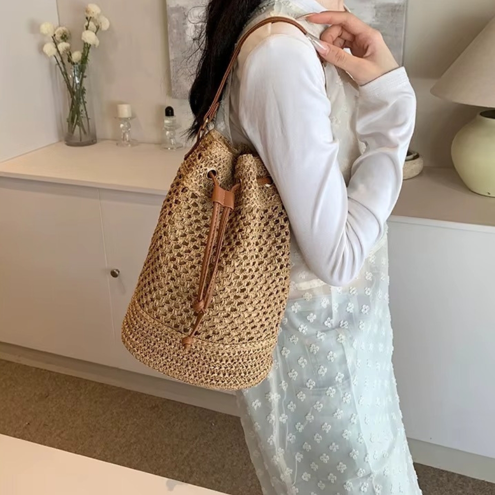 Sac en paille seau ajouré avec cordon coulissant porté à l'épaule, couleur naturelle, détail du tressage et anse en cuir