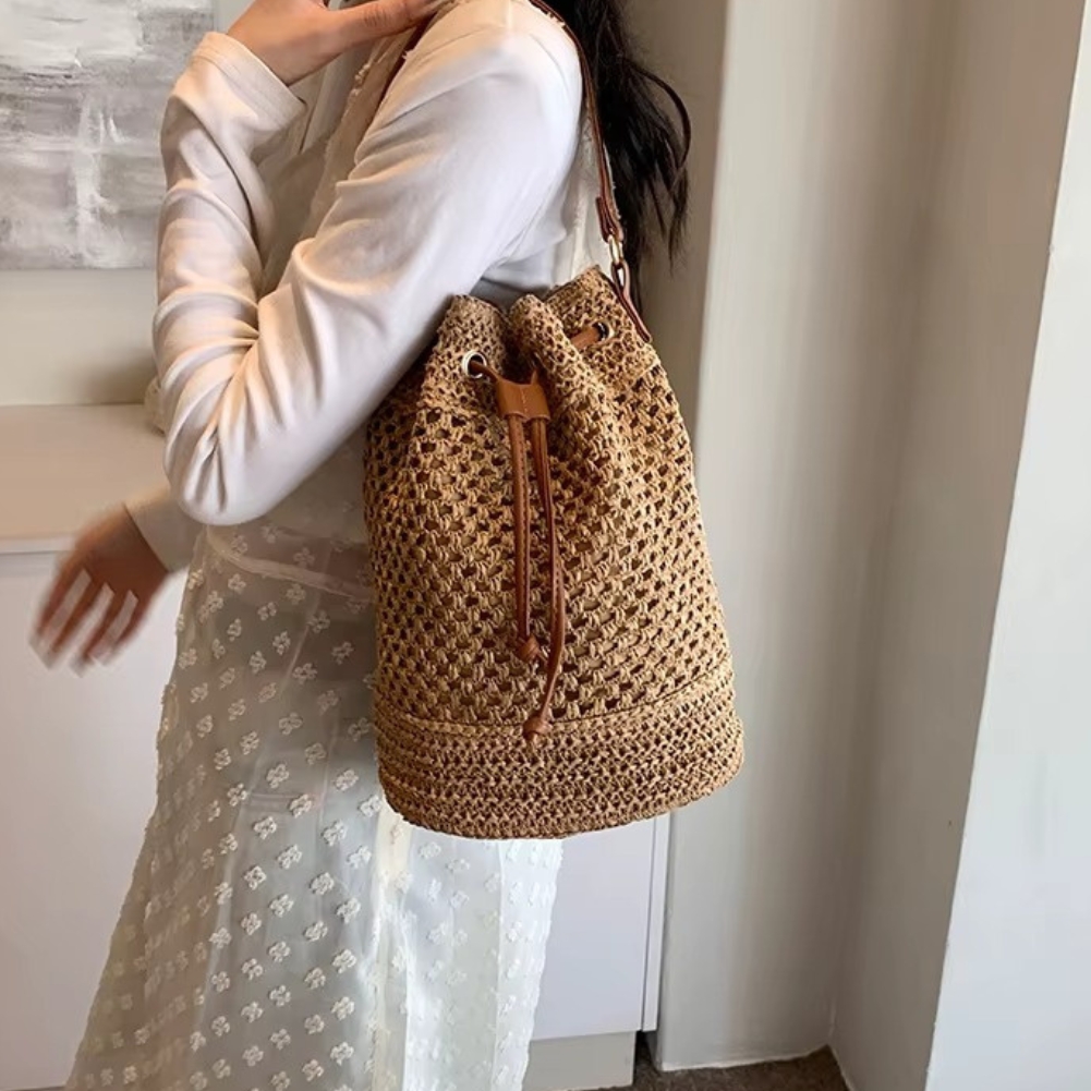 Sac en paille seau ajouré avec cordon coulissant porté sur l'épaule