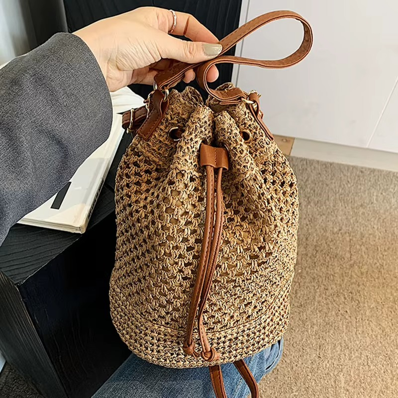 Sac en paille seau ajouré Rosemonde avec cordon coulissant et poignée en cuir tenue à la main
