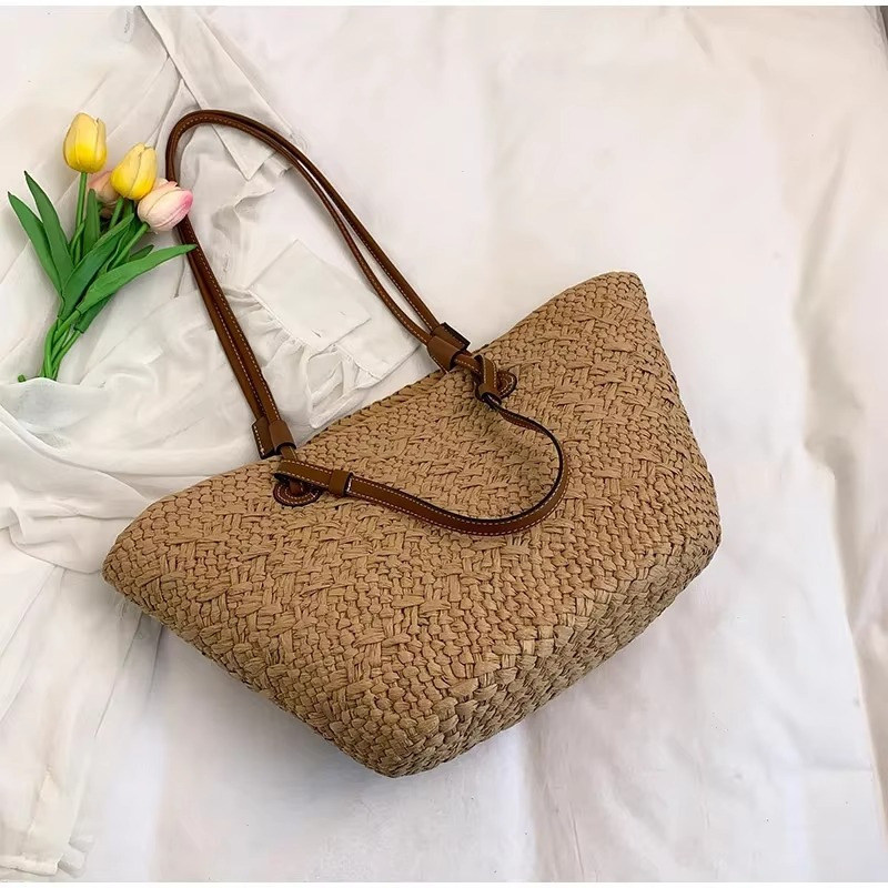 Sac en paille style français grande capacité Manon avec anses en cuir marron posé sur tissu blanc avec bouquet de tulipes jaunes et roses