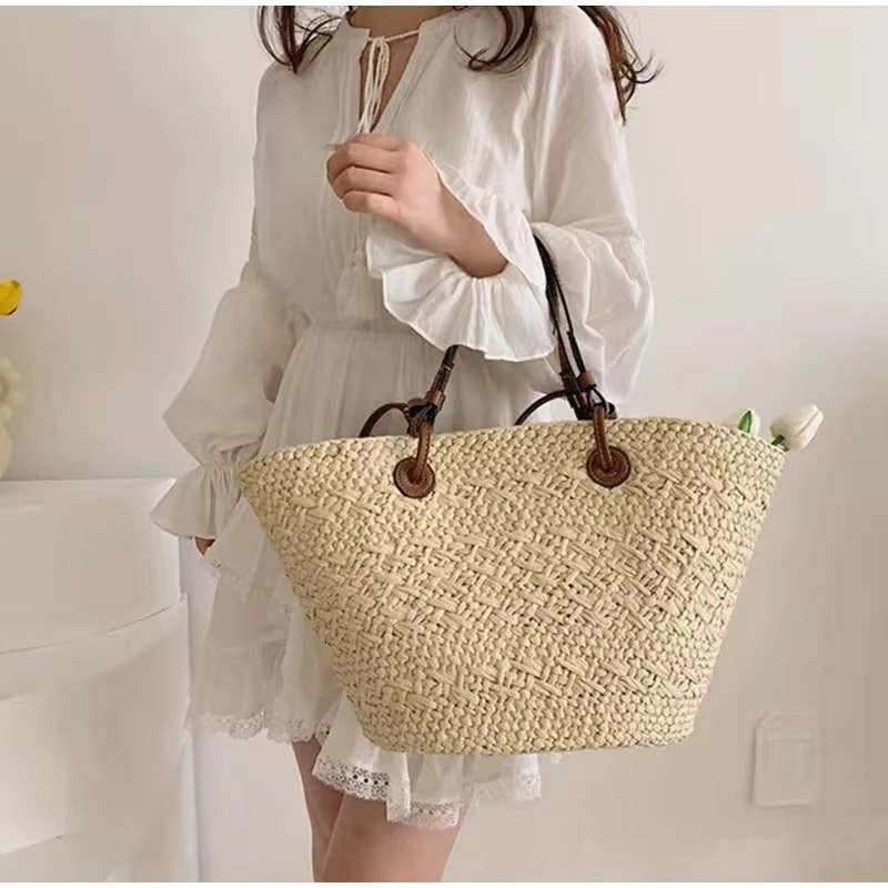 Sac en paille style français grande capacité Manon porté à la main avec anses marron foncé, porté par une femme en robe blanche