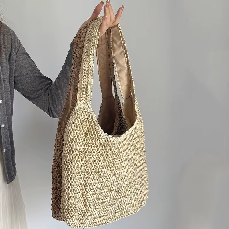 Sac En Paille Tissée Grande Capacité Double Anse – Camélia Sac en paille tissée grande capacité double anse modèle Camélia porté à la main, vue de côté montrant la texture tressée et la doublure intérieure beige