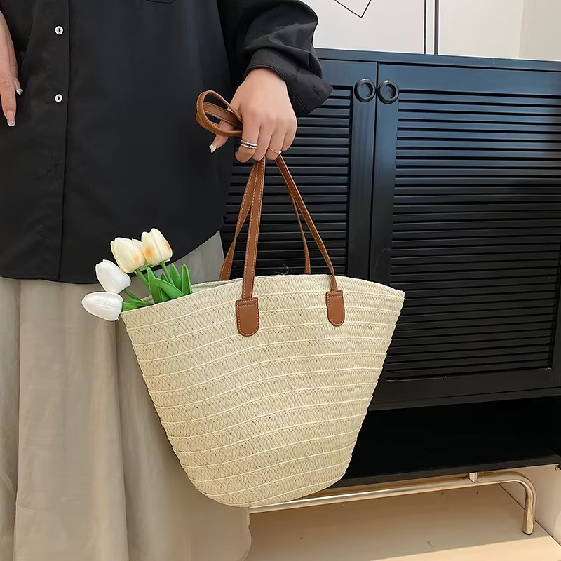Sac en paille tressée bohème grande capacité Océane avec anses marron porté à la main avec des tulipes blanches à l'intérieur
