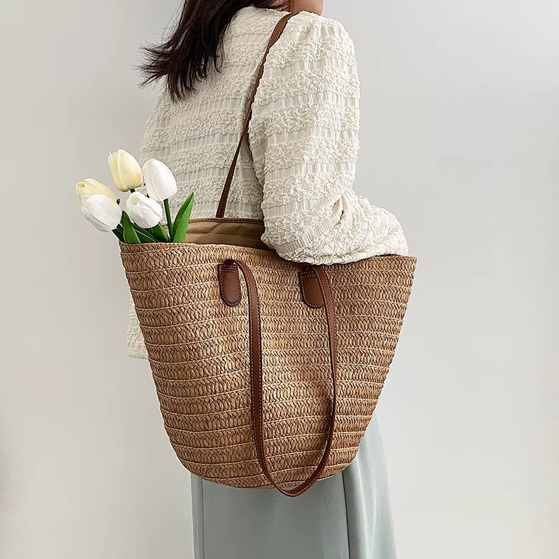 Sac en paille tressée bohème grande capacité Océane porté épaule avec anses en cuir marron et bouquet de tulipes blanches à l'intérieur