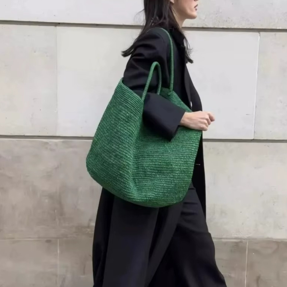 Sac En Paille Tressée Grand Fourre-Tout Plage – Valentine Sac en paille tressée grand fourre-tout plage vert porté sur l'épaule par une femme en manteau noir
