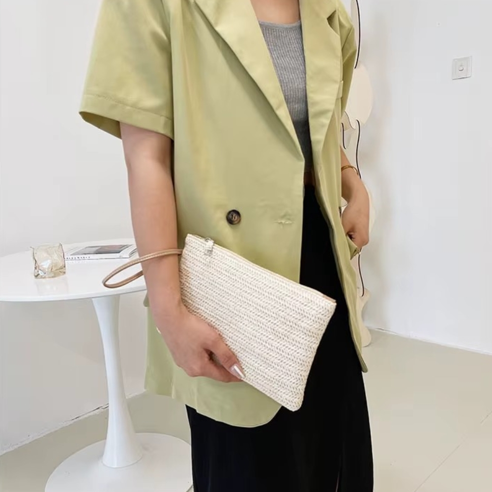 Sac En Paille Tressée Pochette Zippée Porte-Monnaie – Emma Sac en paille tressée pochette zippée beige tenue à la main par une personne portant une veste jaune clair