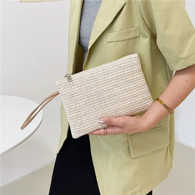 Sac En Paille Tressée Pochette Zippée Porte-Monnaie – Emma Sac en paille tressée pochette zippée beige tenue à la main par une personne portant une veste verte clair