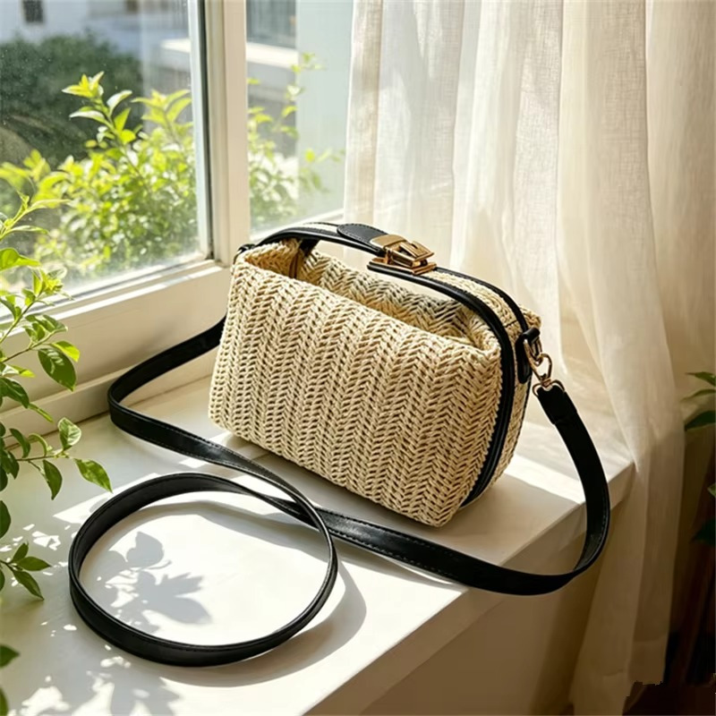 Sac en paille vintage rigide beige avec poignée et fermoir doré, bandoulière fine noire, posé sur un rebord de fenêtre